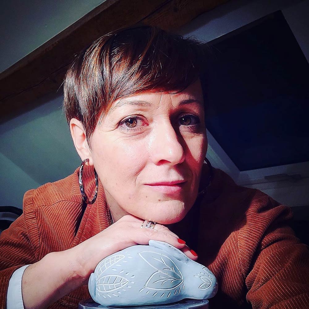 La céramiste - Victoria Céramique Portrait de la céramiste avec la main posée sur un lapin bleu en faïence