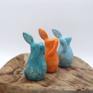 Trois lapins de la sagesse en faïence engobés en turquoise, bleu et orange