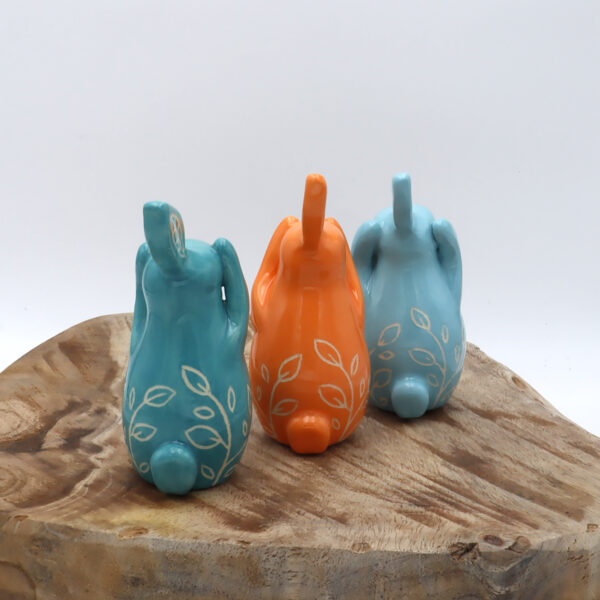 Trois lapins de la sagesse en faïence engobés en turquoise, bleu et orange