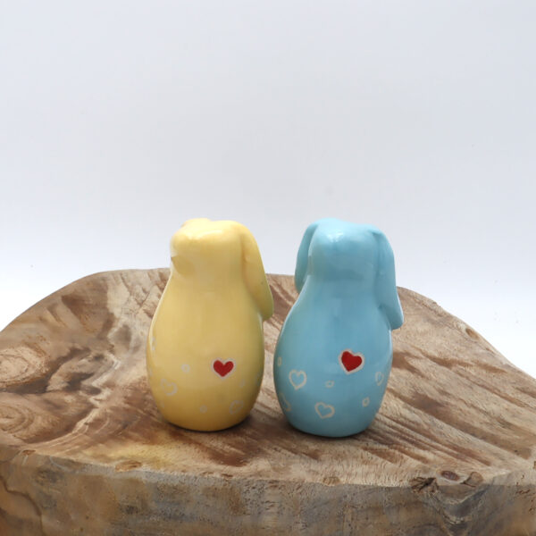 Deux lapins de faïence blanche engobé de jaune et de bleu avec des cœurs rouges