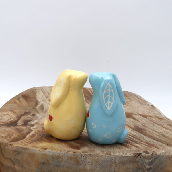 Deux lapins de faïence blanche engobé de jaune et de bleu avec des cœurs rouges
